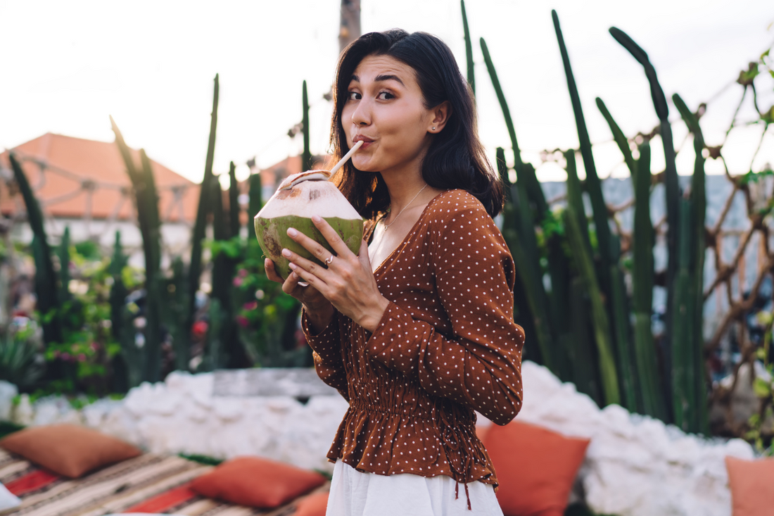 A girl drinking organic coconut water with a straw.