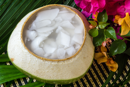 Organic coconut water in a young coconut shell with flowers aside.